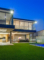 Two storey home at dusk with large glass opening doors and glass pool fencing