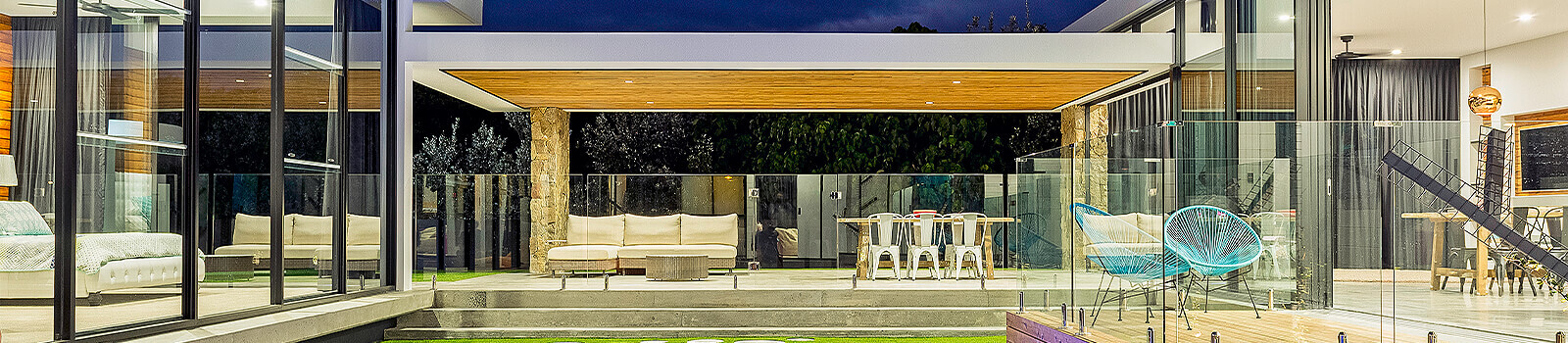 Well lit house at night with glass fencing